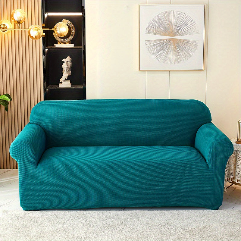 Calma cover in the option labelled Olive Green, shown in blue-green; front view of the fitted sofa cover