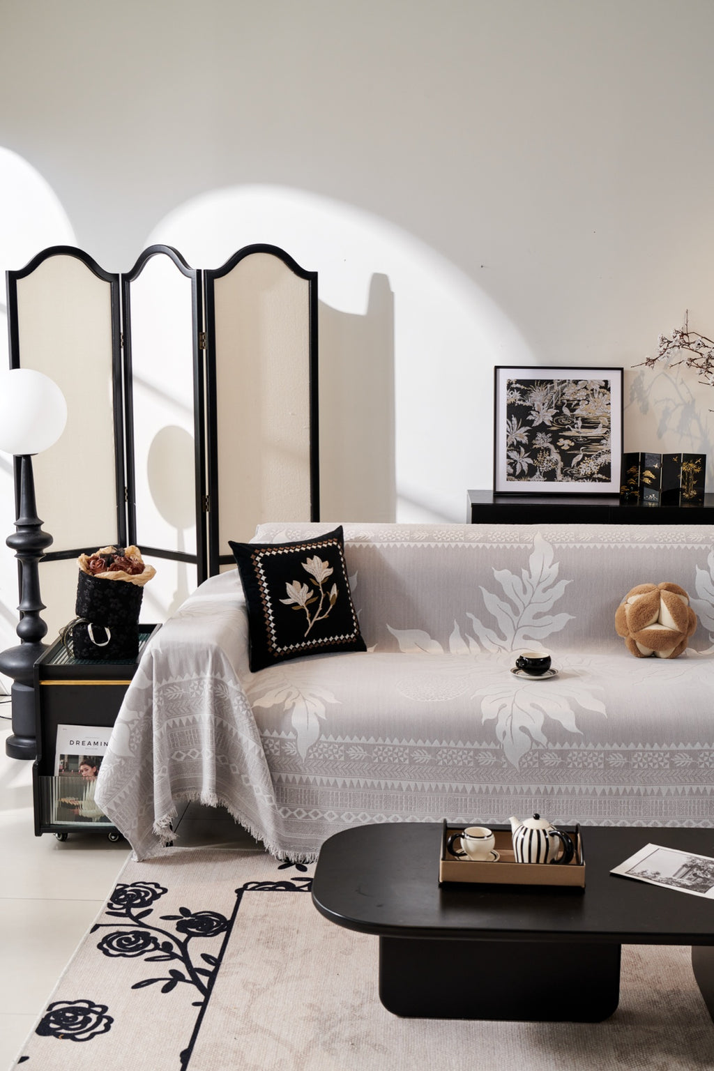 Silver-and-cream Amalfi leafy throw draped over a sofa with a decorative border and fringe