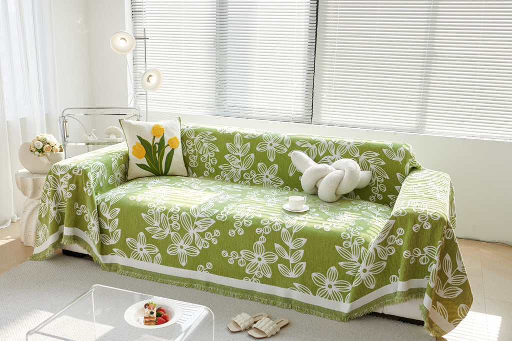 Wide front view of a sofa draped with the Apple Green Celia floral vine throw