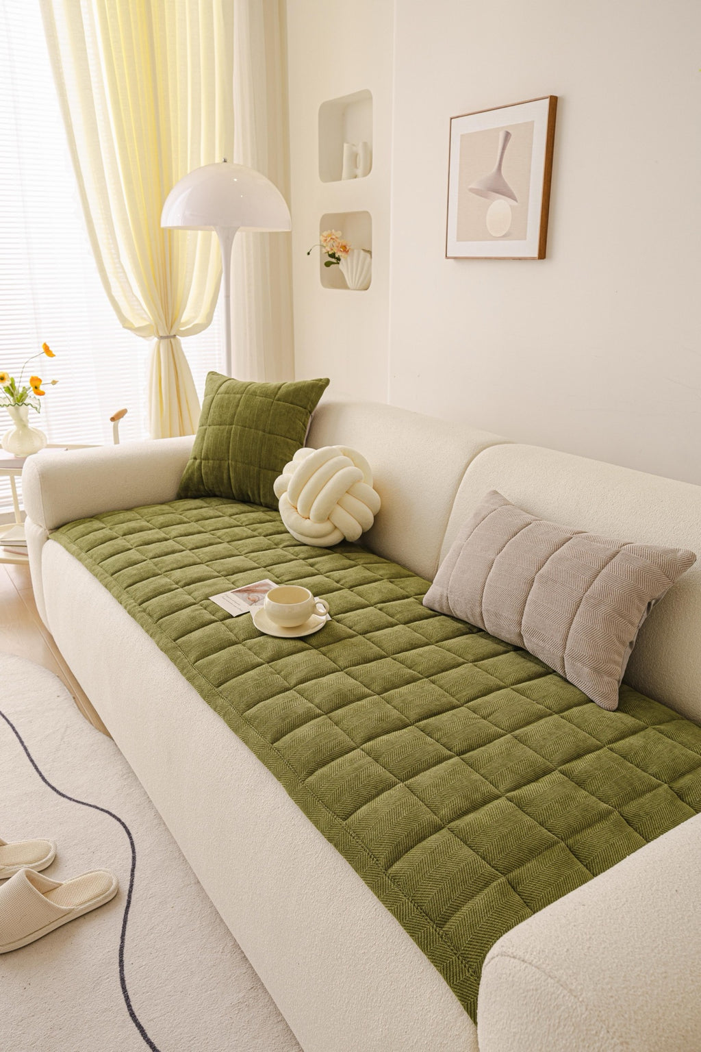 An olive green Haven quilted panel laid across a cream sofa seat with styled cushions