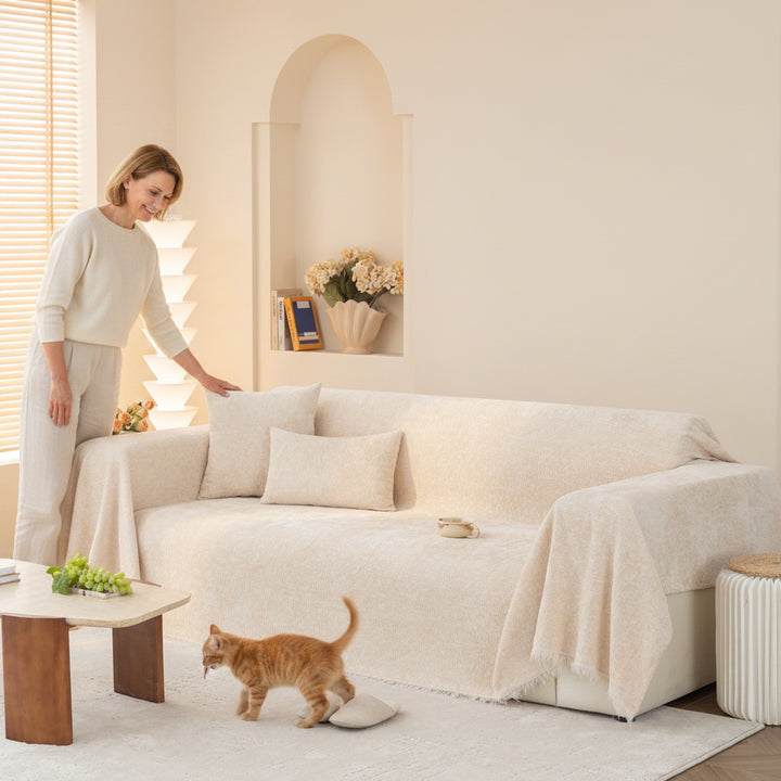 Ivory Cream Solene sofa throw draped over a sofa beside a person and cat